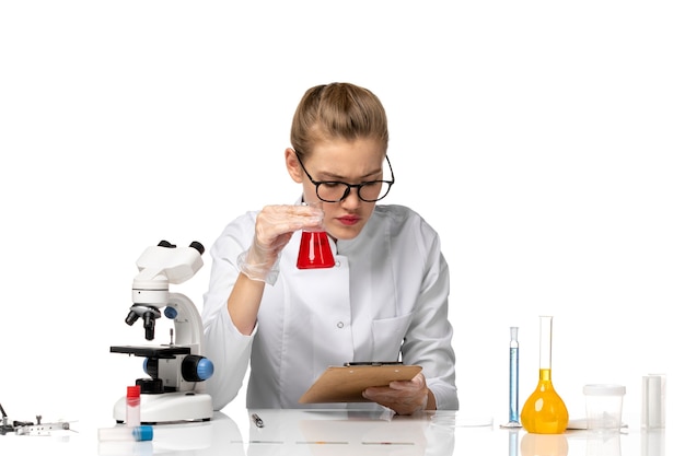 Front view female doctor in white medical suit working with solutions on a light white space