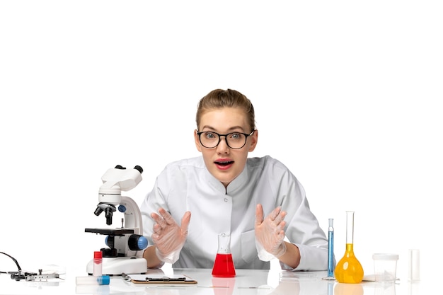 Front view female doctor in white medical suit working with solutions on light white space