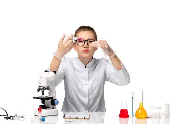 Front view female doctor in white medical suit working with solutions on white floor pandemic covid- disease health virus