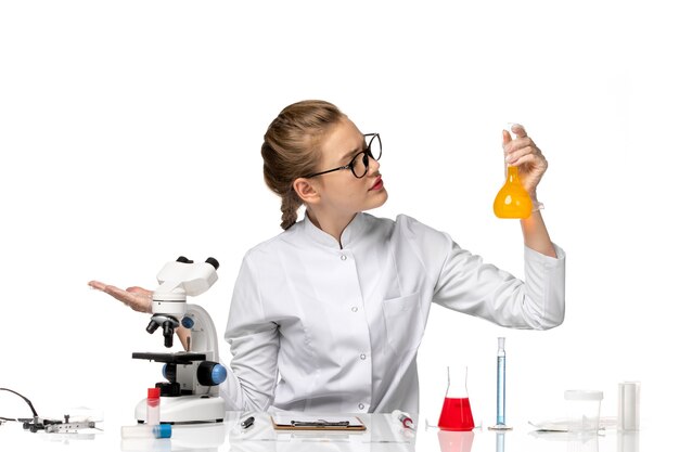 Front view female doctor in white medical suit working with solutions on a white space