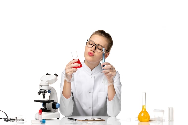 Front view female doctor in white medical suit working with solutions on the white space