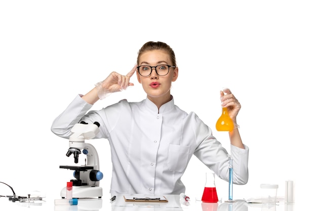 Front view female doctor in white medical suit working with solutions on the white space