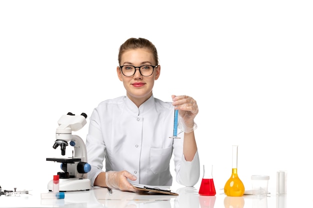 Foto gratuita medico femminile di vista frontale in vestito medico bianco che lavora con le soluzioni sullo spazio bianco