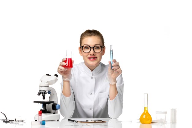 Front view female doctor in white medical suit working with solutions on white space