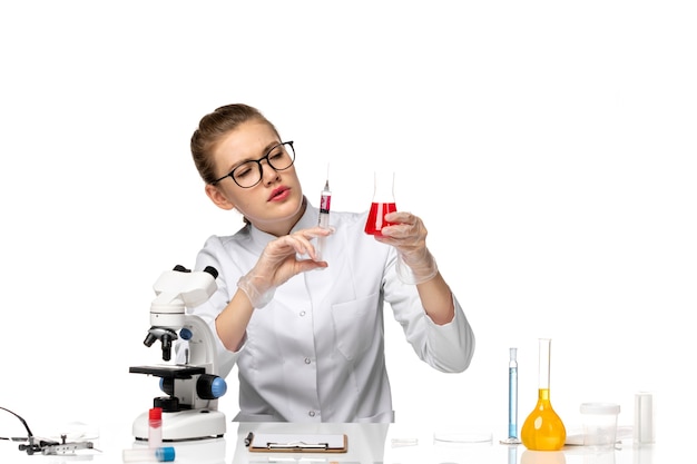 Вид спереди женщина-врач в белом медицинском костюме, работающая с растворами на белом пространстве