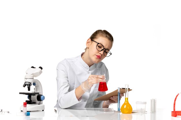 Front view female doctor in white medical suit working with solutions on white space