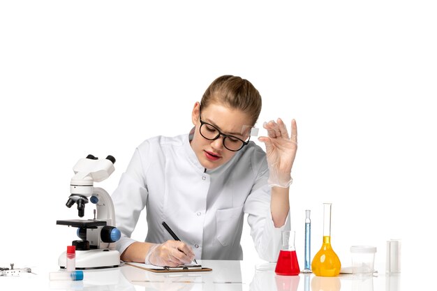 Front view female doctor in white medical suit writing on white space