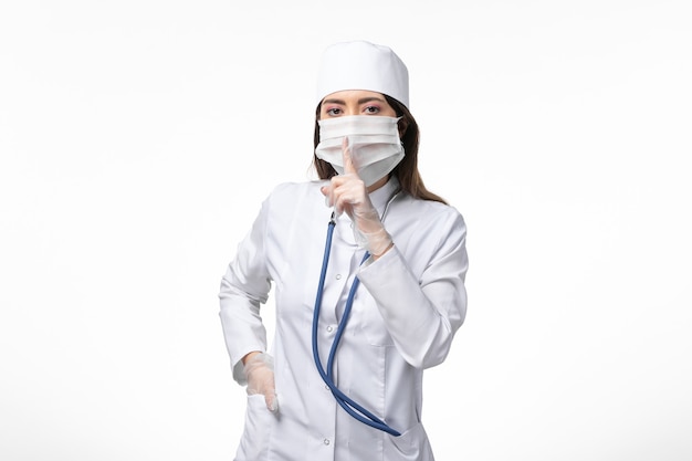 ホワイトデスク病コビパンデミック病ウイルスのコロナウイルスによるマスク付きの白い無菌医療スーツの正面図女性医師