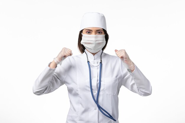 白い壁の病気の病気のパンデミックコビッドウイルスのコロナウイルスによるマスク付きの白い無菌医療スーツの正面図の女性医師