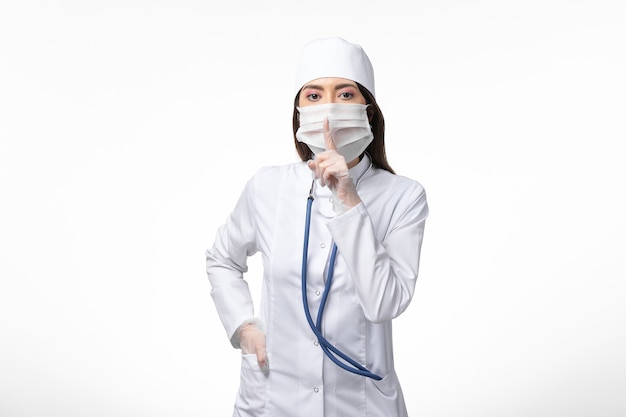 ライトホワイトウォール病のcovid-pandemicウイルス病によるマスク付きの白い無菌医療スーツの正面図の女性医師