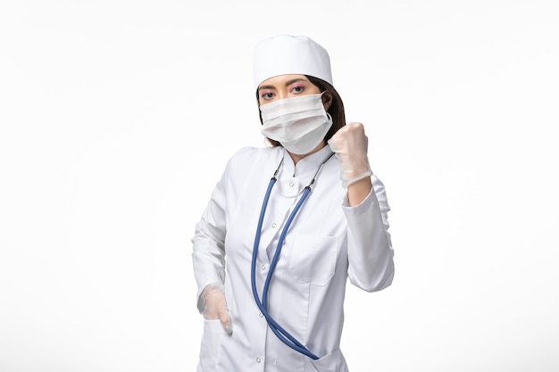 白い机の病気のcovid-pandemicウイルス病のためのマスク付きの白い無菌医療スーツの正面図の女性医師