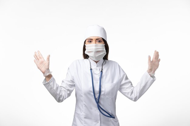 Вид спереди женщина-врач в белом стерильном медицинском костюме с маской из-за covid- на белой стене, болезнь covid- пандемия