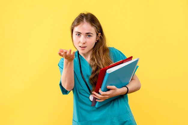 Medico femminile vista frontale con analisi sulla salute dell'ospedale medico infermiere sfondo giallo