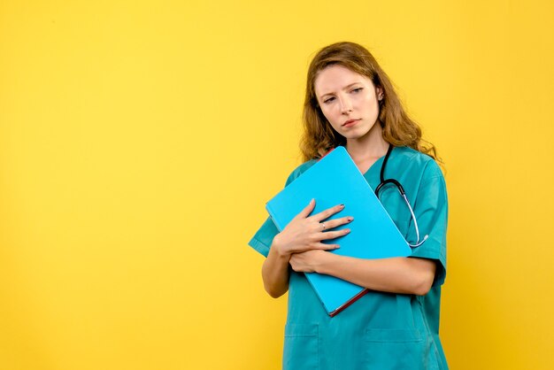 Front view of female doctor with analyzes on a yellow wall