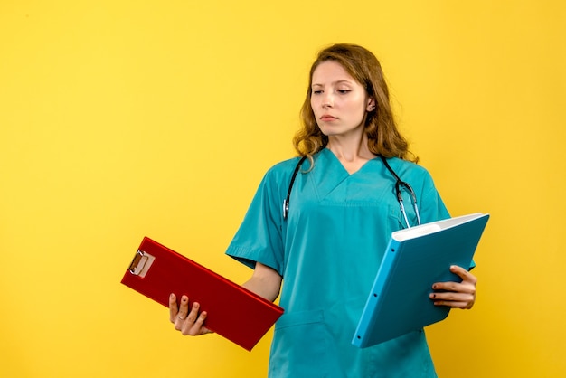 Front view of female doctor with analyzes on yellow wall