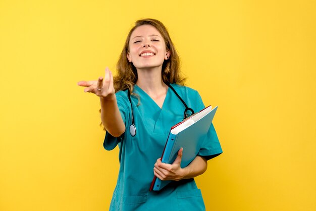 Front view of female doctor with analyzes on yellow wall