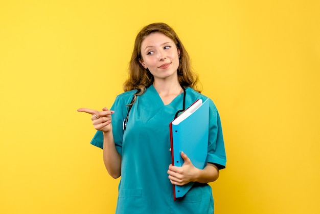 Front view of female doctor with analyzes on yellow wall