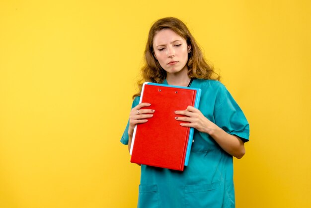 Front view of female doctor with analyzes on yellow wall