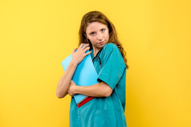 Front view of female doctor with analyzes on yellow wall