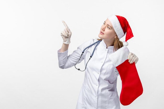 Front view of female doctor with big holiday sock on a white wall
