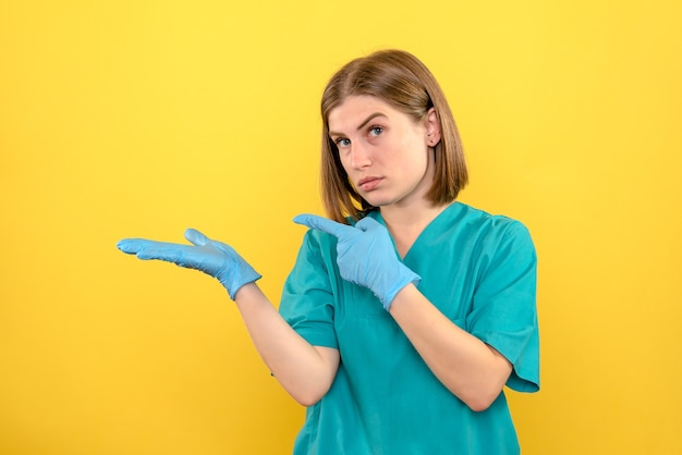 Front view female doctor with blue gloves on a yellow space