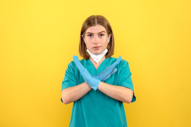 Вид спереди женщина-врач с синими перчатками на желтом пространстве
