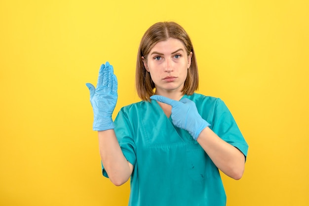 Front view female doctor with blue gloves on yellow space