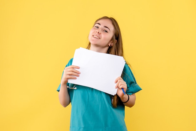 Front view female doctor with documentation on a yellow background nurse health hospital