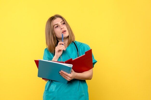 Front view female doctor with documents on a yellow space