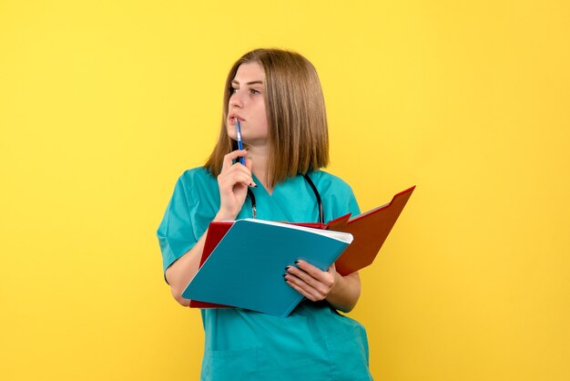 Front view female doctor with documents on the yellow space