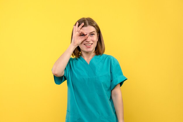 Front view of female doctor with excited expression on yellow wall