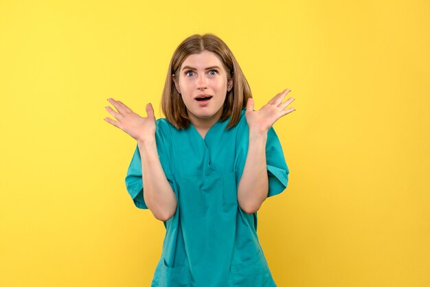 Front view of female doctor with excited expression on yellow wall