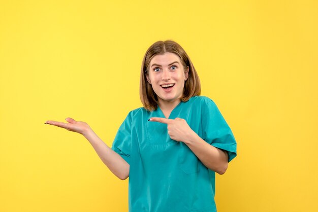 Front view of female doctor with excited face on yellow wall