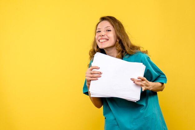 Front view female doctor with files on a yellow space