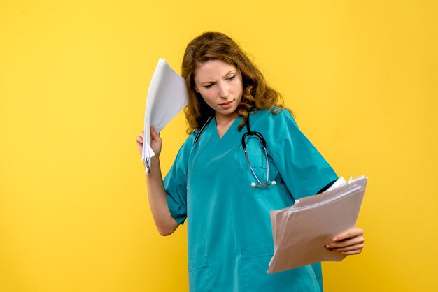 Вид спереди женщина-врач с файлами на желтом пространстве