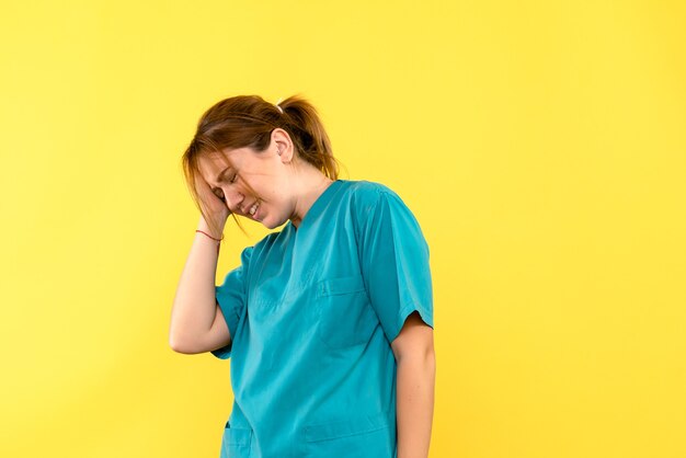 Front view of female doctor with headache on yellow wall