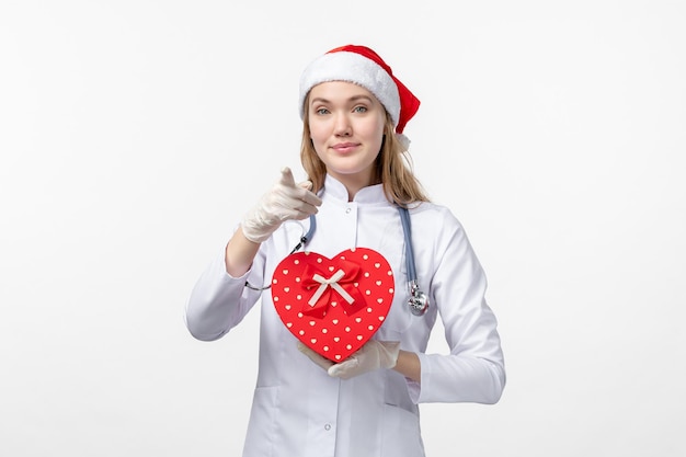 Front view of female doctor with holiday present on a white wall