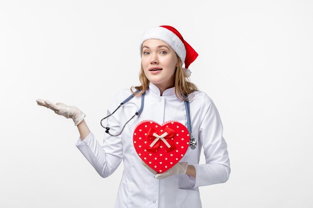 Front view of female doctor with holiday present on white wall