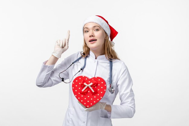 Front view of female doctor with holiday present on white wall