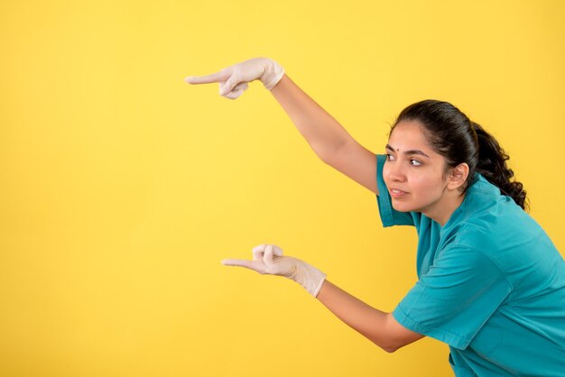 Front view female doctor with latex gloves pointing with finger left