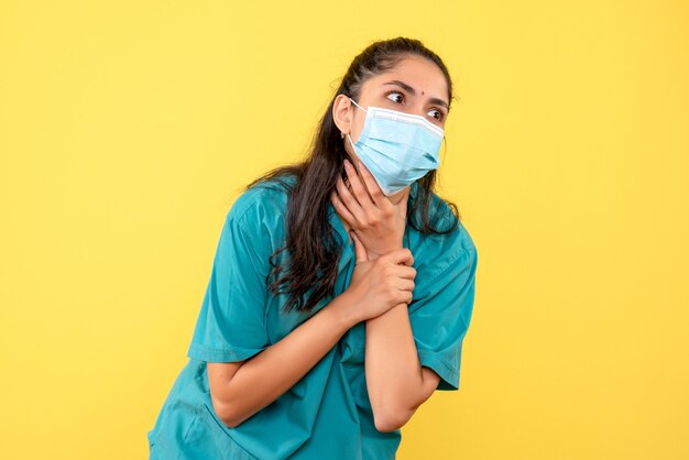 Front view female doctor with mask holding her throat standing