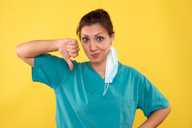 Front view female doctor with mask on yellow background