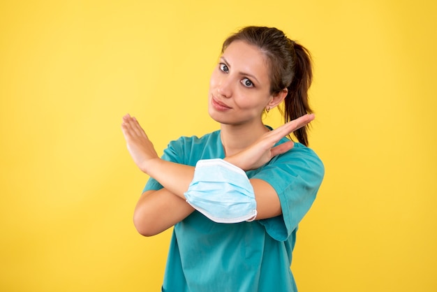 Foto gratuita medico femminile di vista frontale con la mascherina su priorità bassa gialla