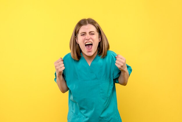 Front view of female doctor with rejoicing face on yellow wall