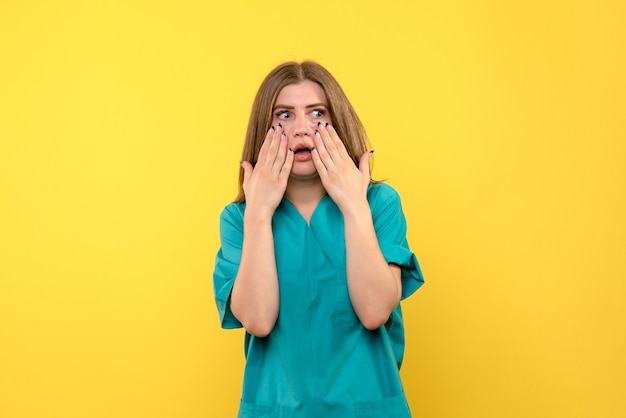 Front view of female doctor with scared face on yellow wall