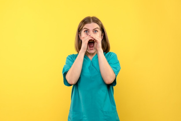 Front view of female doctor with screaming expression on yellow wall