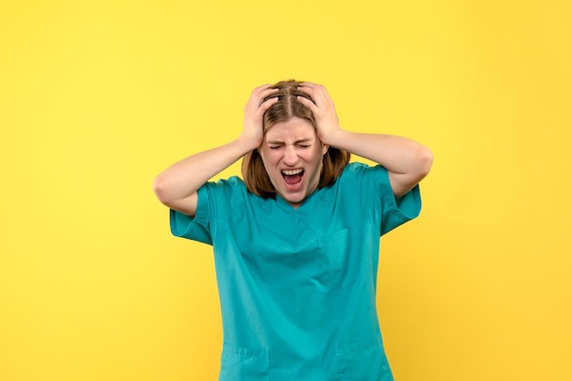 Front view of female doctor with screaming face on yellow wall
