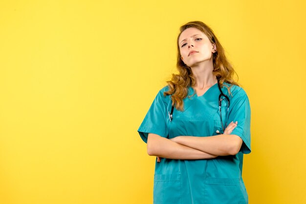 Вид спереди женщина-врач с серьезным лицом на желтом пространстве