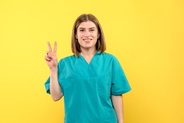 Front view of female doctor with smiling expression on yellow wall