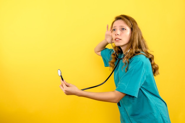 Вид спереди женщина-врач со стетоскопом на светло-желтом пространстве